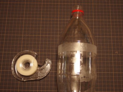 1.5リットルのコーラのペットボトルを利用して扇風機の「羽根」を作ります。まず、飲み口から10cmぐらい下のナナメ部分が終わっている平行な部分で、メンディングテープを一周巻きます。